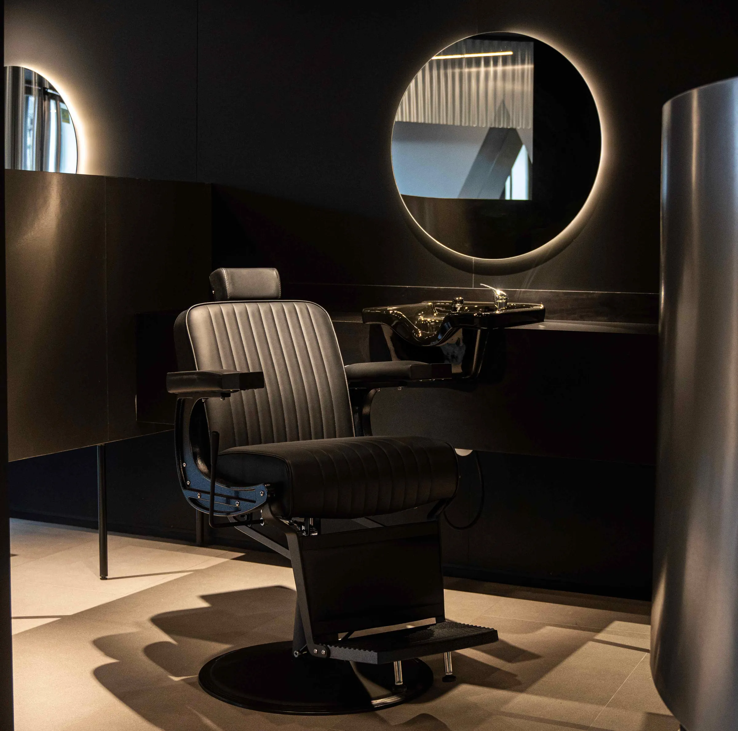 Puesto de barbería con sillón de cuero y espejo redondo